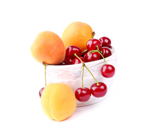 Cherry and apricot in ceramic bowl isolated on white background