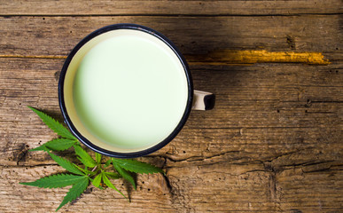 Green milk with marijuana on rustic wooden table