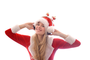A young blonde beautiful girl wears a Santa Claus suit and has headphones on her head. She enjoys...