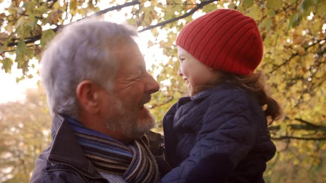 Grandfather Walking With Granddaughter In Autumn Countryside