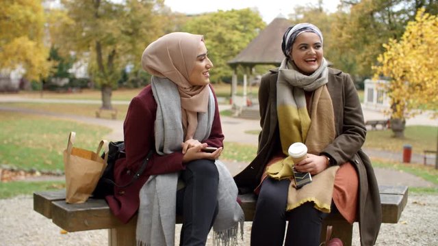 Two British Muslim Women On Lunch Break Meet In Urban Park 