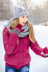 young smiling fashion woman in winter clothes holding smartphone in the background of snow.