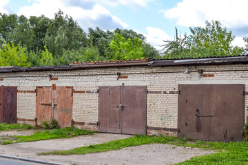 Fototapeta na wymiar A row of brick garages with rusty metal gates. Russia