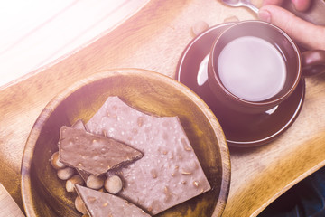 A man sits on the wooden floor, drinking coffee with chocolate. Close-up.