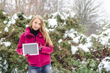 Copy space on her tablet. Beautiful young woman showing tablet and smiling  in winter in the background. Business concept