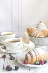 Fototapeta na wymiar Croissants with fresh berries and two cups of coffee