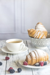 Croissants with fresh berries and a cup of coffee