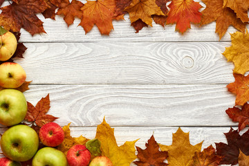 Autumn leaves and apples over old wooden background