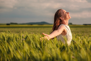 Beautiful woman in white dress on green wheat field