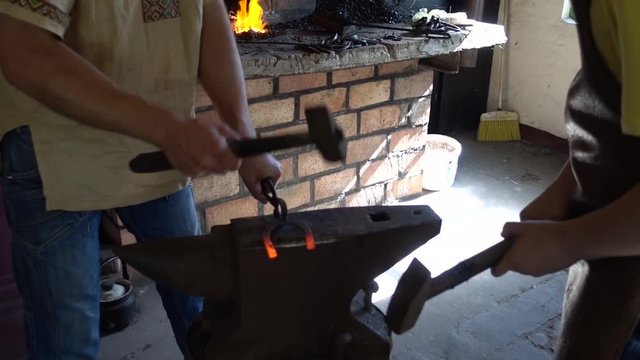 Paired work at forging shop hammering a small horseshoe