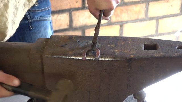 Paired work at forging shop hammering a small horseshoe