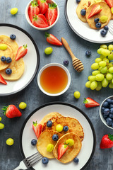 Homemade Pancakes with Blueberry, Strawberry, green Grape and honey syrup. served on plate