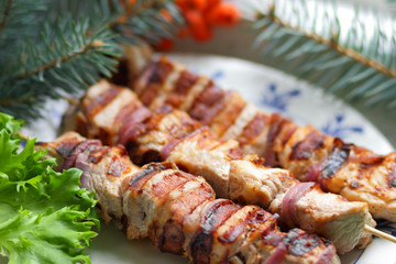 Pork shish kebab with fir branches, rowan and green leaf of lettuce cooked on the grill for Christmas dinner for the designer