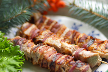 Pork shish kebab with fir branches, rowan and green leaf of lettuce cooked on the grill for Christmas dinner for the designer