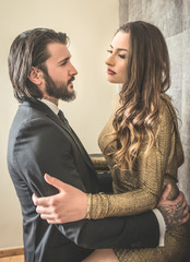 Boudoir couple elegantly dressed embracing each other in doors