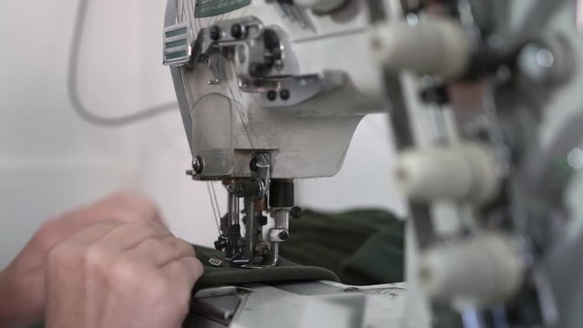 Female tailor works at sewing machine focus change from hands to device, hands of dressmaker stitches cloth, shallow depth of field,concept tailoring, room interior, close up.