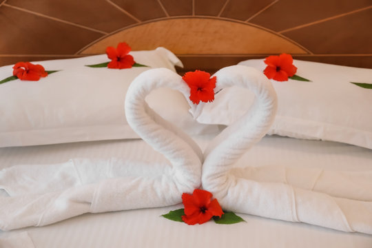 Floral decor and towel swans on bed in hotel room