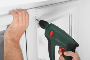Young man installing window screens indoors