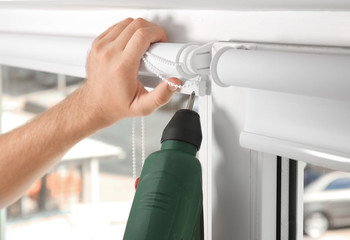 Young man installing window screens indoors