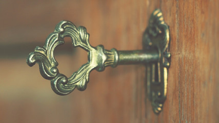 Selective focus, old keyhole and key on a wooden antique door, vintage color tone process