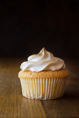 One lemon sponge cup cake with meringue topping isolated on wooden table close up - food background