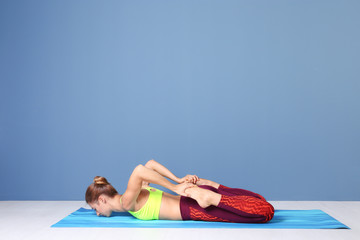 Young woman practicing yoga pose near color wall indoors