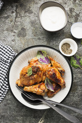 Appetizing chicken pieces in a hot sweet frosting baked in the oven in a baked pumpkin, sour cream and basil in a serving plate on a dark background. Top View.