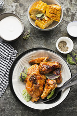 Appetizing chicken pieces in a hot sweet frosting baked in the oven in a baked pumpkin, sour cream and basil in a serving plate on a dark background. Top View.