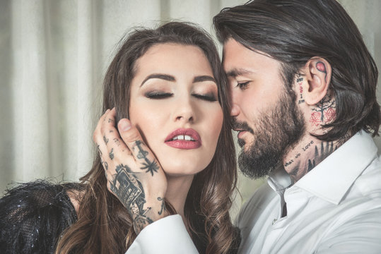 Tattooed man teasing and touching a blonde sensual woman, boudoir couple