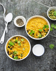 Cream soup from baked juicy young corn with pumpkin seeds, black sesame, cilantro in a bowl with a gray background with sour cream and cutlery. Top View.