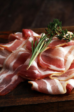 Raw sliced bacon with thyme leaves ready for cooking.
