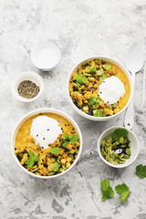 Cream soup from baked juicy young corn with pumpkin seeds, black sesame, cilantro in a bowl with a gray background with sour cream and cutlery. Top View.