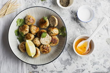 Homemade chicken meatballs with a spicy sour sweet sauce in a plate on the table. Top View.