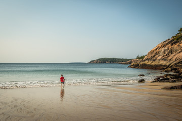 Child on Rocky Beach with Waves in Sand
