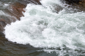 water resources, rafting, travelling concept. rough waters of river are creating underwater swirls in the dangerous stage of rapids with help of big stones and uneven surface