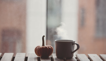 White cup of coffee or tea near a pumpkin