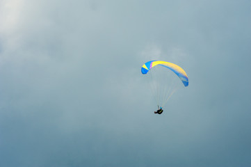 Paraglider flying in the blue sky against the background of clouds. Paragliding in the sky on a sunny day.