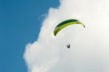 Paraglider flying in the blue sky against the background of clouds. Paragliding in the sky on a sunny day.