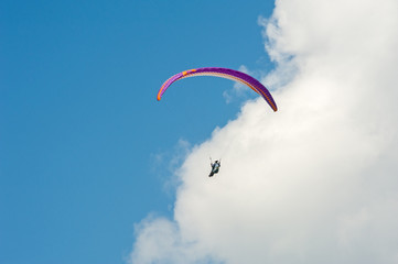 Paraglider flying in the blue sky against the background of clouds. Paragliding in the sky on a sunny day.
