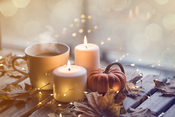cup of coffee or tea near a pumpkin and candles