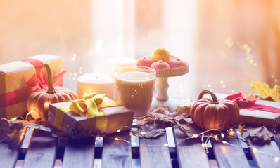 cup of coffee or tea near a pumpkin, gifts and candles