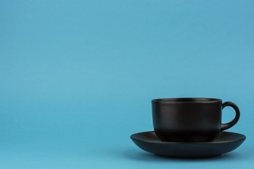 The turquoise background is a black ceramic mug