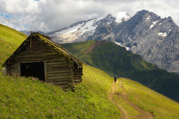 Fototapeta na wymiar Old cabin in Dolomites with Marmolada peak on the background, Italy