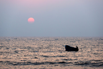 Fisherman sailing in a boat at sunset