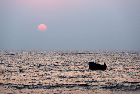 Fisherman sailing in a boat at sunset