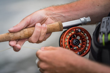 Fliegenrute mit Rolle und Schnur in der Hand gehalten von Angler beim Angeln
