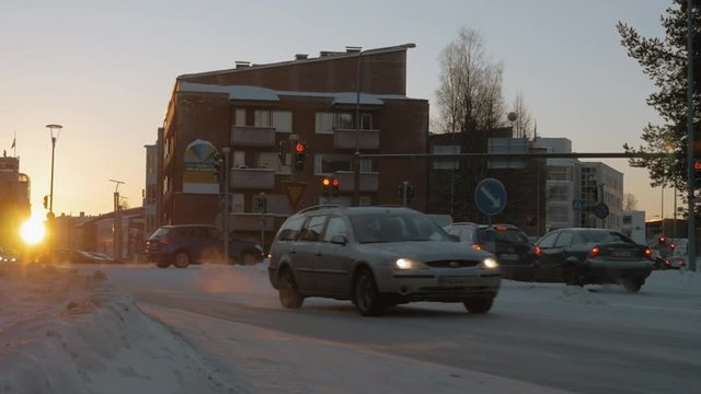 ROVANIEMI, FINLAND - JANUARY 06, 2017: Slow motion shot of road traffic in winter city at sunset. Cars driving and others stop at red signal of traffic lights