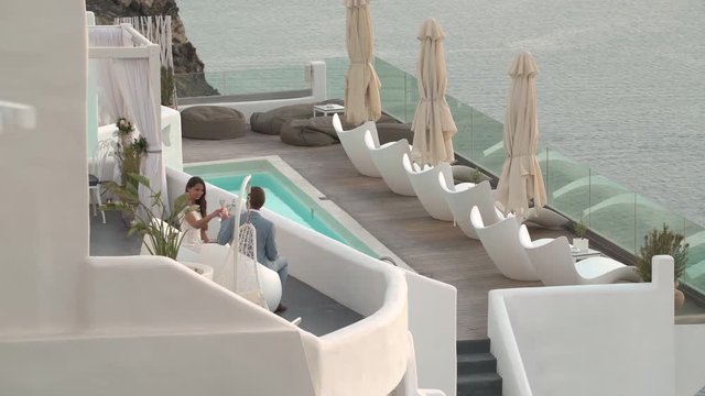 4k travel video newlywed couple drinking champagne on luxury terrace overlooking the sea
