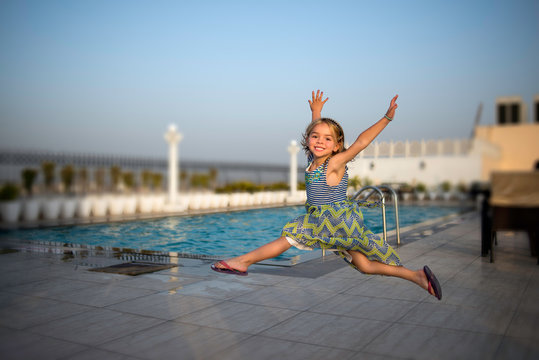 Blonde Child Jumping Close To The Pool