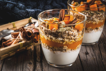 Traditional autumn dishes, spicy pumpkin pie overnight oatmeal with cinnamon, anise and maple syrup. In portioned glasses, on wooden old rustic table. Copy space
